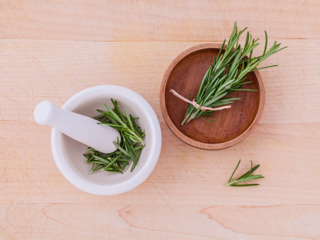fresh rosemary herbal medicine in mortar and wooden bowl on wood